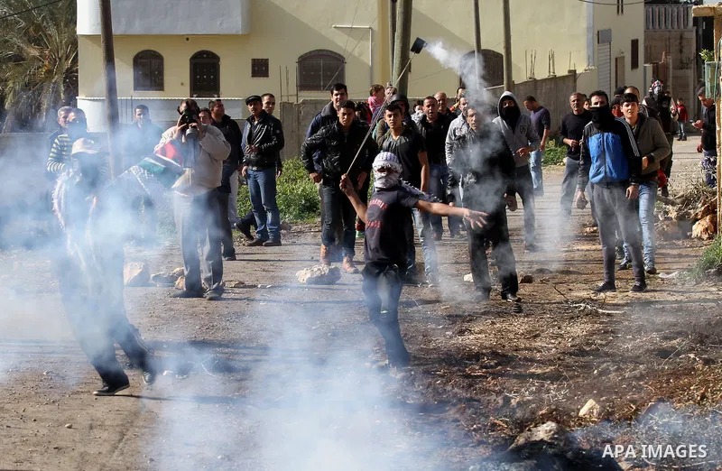 A Palestinian protester uses a slingshot to throw back a canisters fired by Israeli secrity forces during clashes following a protest against the expropriation of Palestinian land by Israel in the West Bank village of Ka...