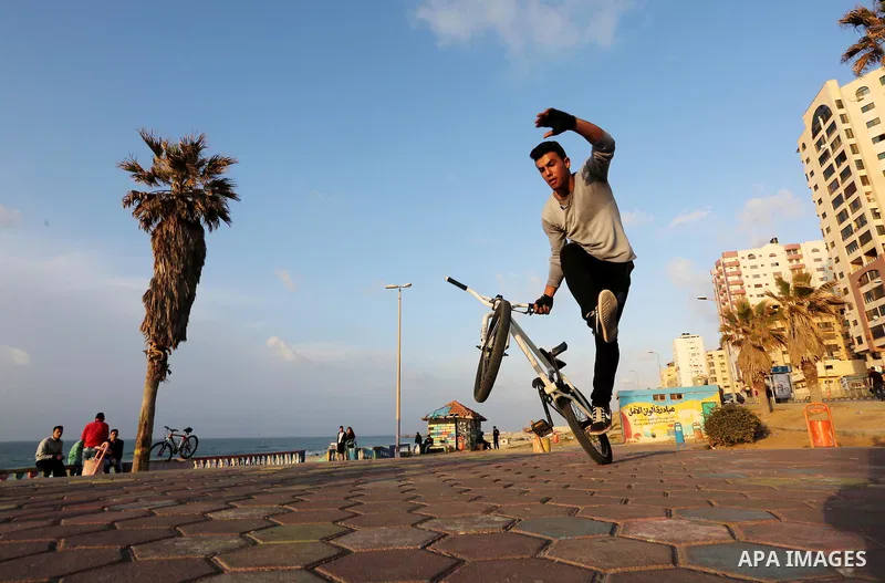 A Palestinian youth performs stunts with bicycles on the beach of the Mediterranean Sea in Gaza City on Jan. 22, 2016. Photo by Mohammed Asad