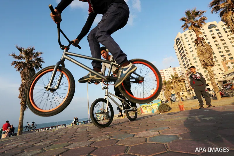 Palestinian youths perform stunts with bicycles on the beach of the Mediterranean Sea in Gaza City on Jan. 22, 2016. Photo by Mohammed Asad
