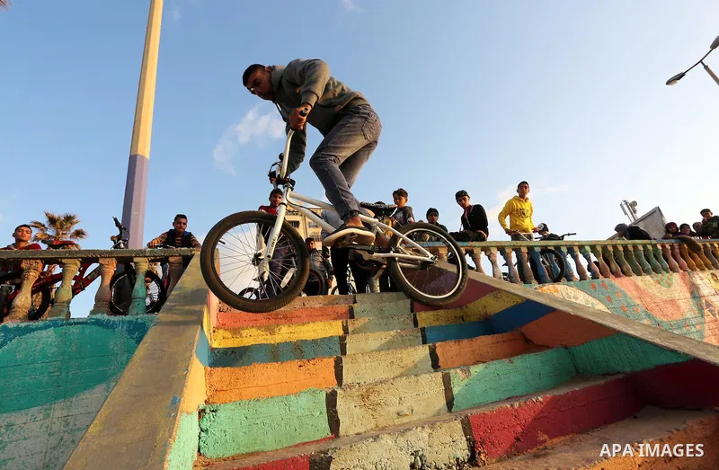 A Palestinian youth performs stunts with bicycles on the beach of the Mediterranean Sea in Gaza City on Jan. 22, 2016. Photo by Mohammed Asad