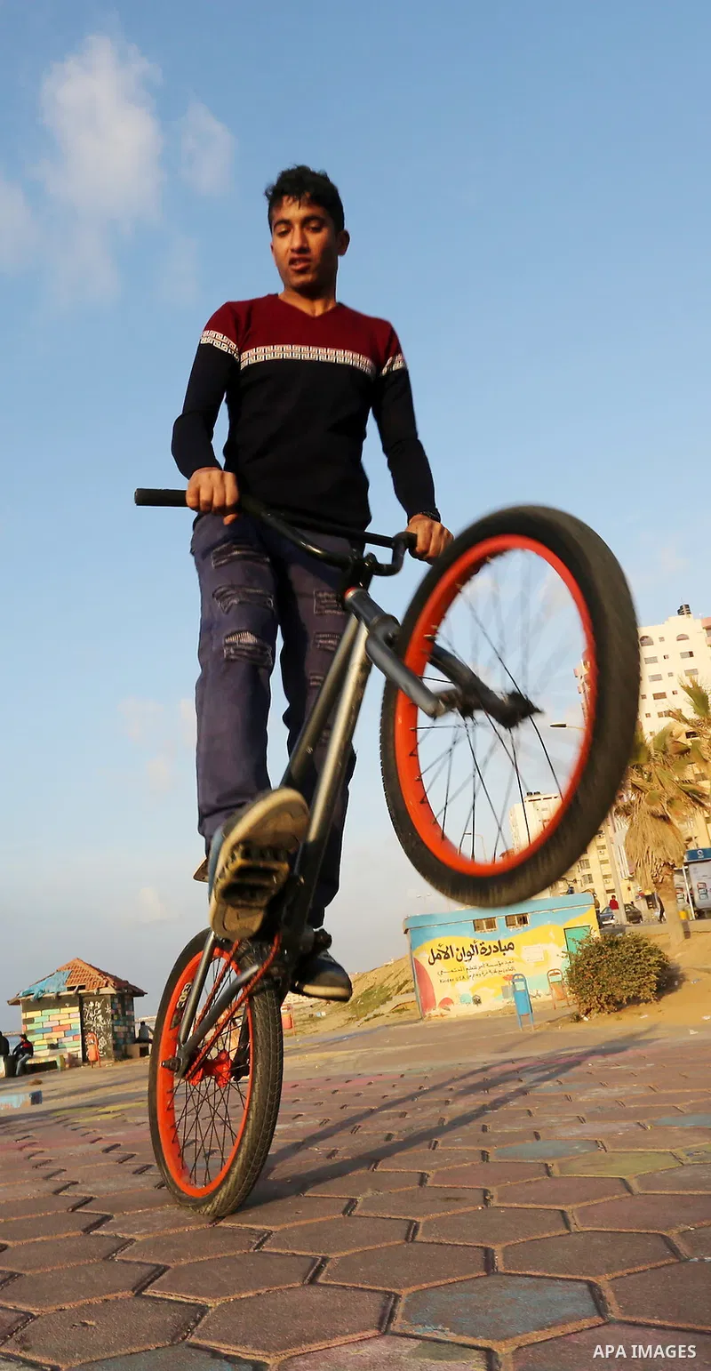 A Palestinian youth performs stunts with bicycles on the beach of the Mediterranean Sea in Gaza City on Jan. 22, 2016. Photo by Mohammed Asad