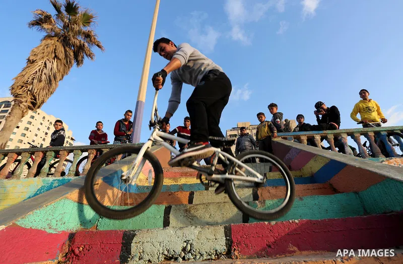 A Palestinian youth performs stunts with bicycles on the beach of the Mediterranean Sea in Gaza City on Jan. 22, 2016. Photo by Mohammed Asad