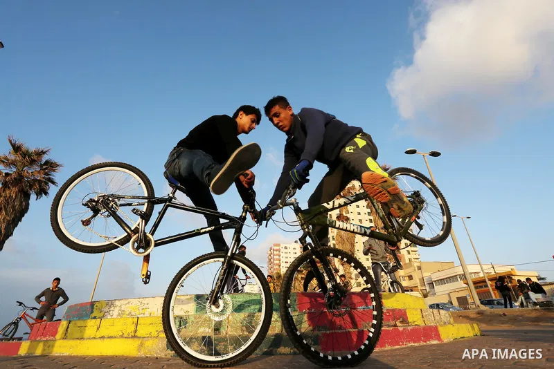 Palestinian youths perform stunts with bicycles on the beach of the Mediterranean Sea in Gaza City on Jan. 22, 2016. Photo by Mohammed Asad