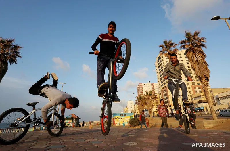 Palestinian youths perform stunts with bicycles on the beach of the Mediterranean Sea in Gaza City on Jan. 22, 2016. Photo by Mohammed Asad