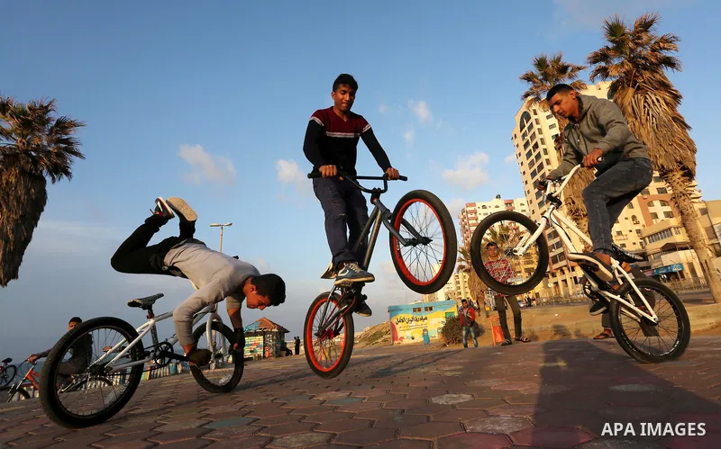 Palestinian youths perform stunts with bicycles on the beach of the Mediterranean Sea in Gaza City on Jan. 22, 2016. Photo by Mohammed Asad