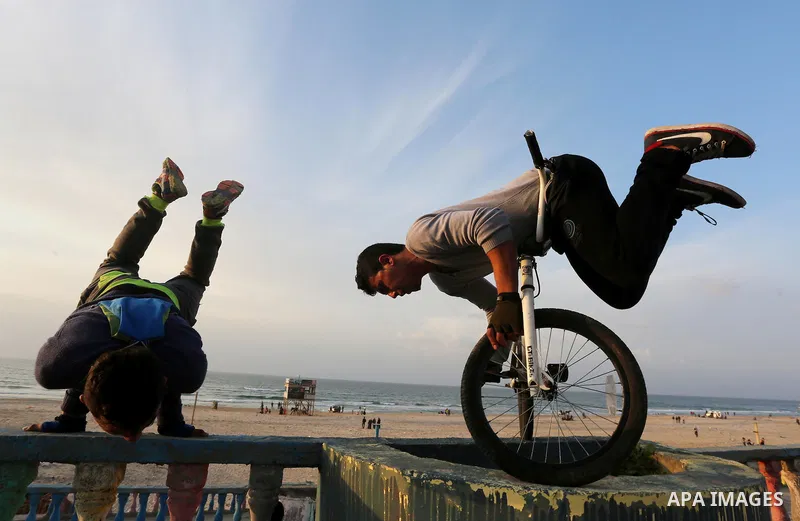 A Palestinian youth performs stunts with bicycles on the beach of the Mediterranean Sea in Gaza City on Jan. 22, 2016. Photo by Mohammed Asad