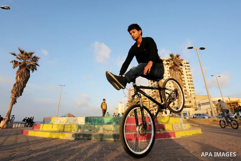 A Palestinian youth performs stunts with bicycles on the beach of the Mediterranean Sea in Gaza City on Jan. 22, 2016. Photo by Mohammed Asad