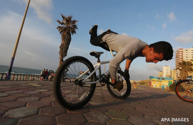 A Palestinian youth performs stunts with bicycles on the beach of the Mediterranean Sea in Gaza City on Jan. 22, 2016. Photo by Mohammed Asad