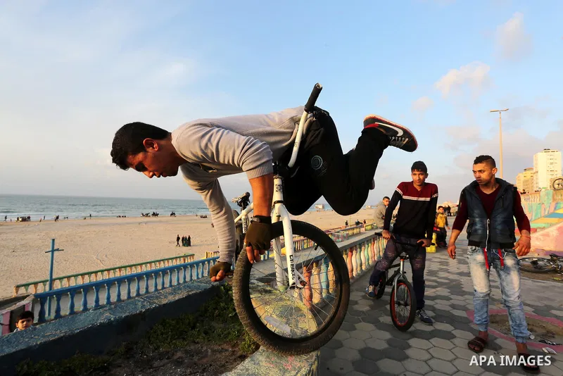 A Palestinian youth performs stunts with bicycles on the beach of the Mediterranean Sea in Gaza City on Jan. 22, 2016. Photo by Mohammed Asad
