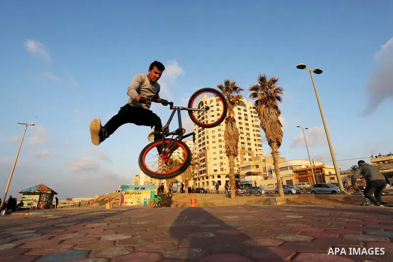 A Palestinian youth performs stunts with bicycles on the beach of the Mediterranean Sea in Gaza City on Jan. 22, 2016. Photo by Mohammed Asad