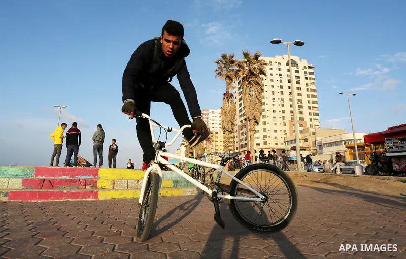A Palestinian youth performs stunts with bicycles on the beach of the Mediterranean Sea in Gaza City on Jan. 22, 2016. Photo by Mohammed Asad