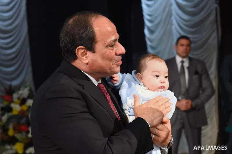 Egyptian President Abdel-Fattah el-Sissi holds a child as he presents a medal to the widow of a policeman killed in militant attacks, at a ceremony marking Police Day, which falls on Jan. 25, the anniversary of the 2011...