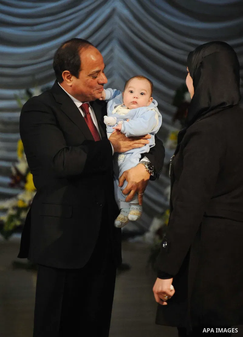 Egyptian President Abdel-Fattah el-Sissi holds a child as he presents a medal to the widow of a policeman killed in militant attacks, at a ceremony marking Police Day, which falls on Jan. 25, the anniversary of the 2011...