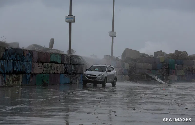 A Palestinian man drives his car in a street flooded by rain water in Gaza City, January 24, 2016. Photo by Mohammed Asad