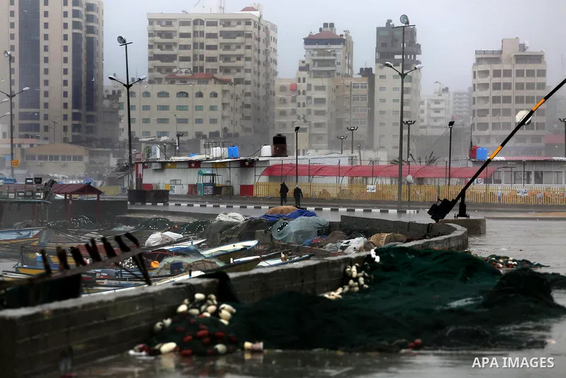 Palestinians walk at the seaport during a rainy day, in Gaza City, January 24, 2016. Photo by Mohammed Asad