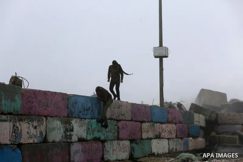 Palestinians stand at the seaport during a rainy day, in Gaza City, January 24, 2016. Photo by Mohammed Asad