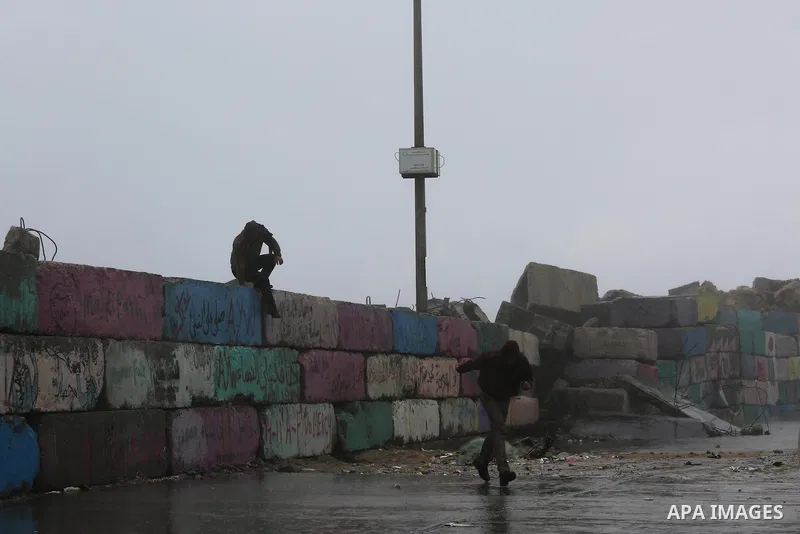 Palestinians stand at the seaport during a rainy day, in Gaza City, January 24, 2016. Photo by Mohammed Asad
