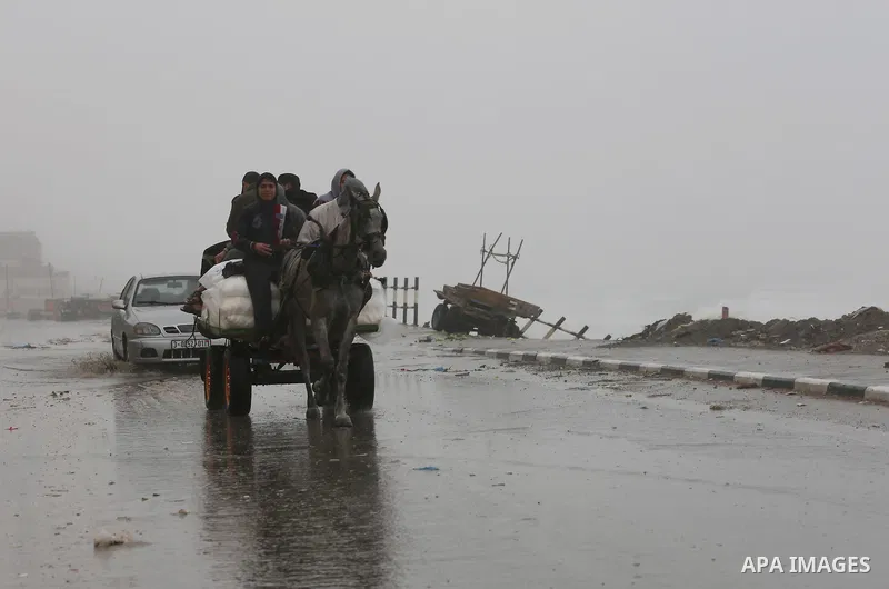 Palestinian men ride a donkey cart in a street flooded by rain water, in Gaza City, January 24, 2016. Photo by Mohammed Asad