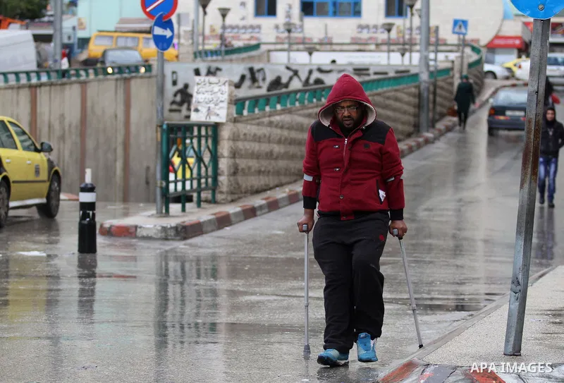 Palestinians walk in a street flooded by rain water, in the West Bank city of Nablus, on January, 24, 2016. Photo by Nedal Eshtayah