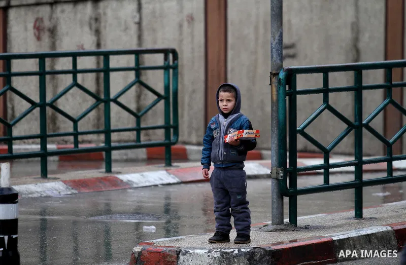 Palestinians walk in a street flooded by rain water, in the West Bank city of Nablus, on January, 24, 2016. Photo by Nedal Eshtayah