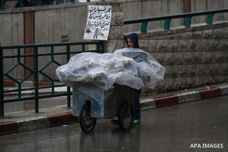 Palestinians walk in a street flooded by rain water, in the West Bank city of Nablus, on January, 24, 2016. Photo by Nedal Eshtayah