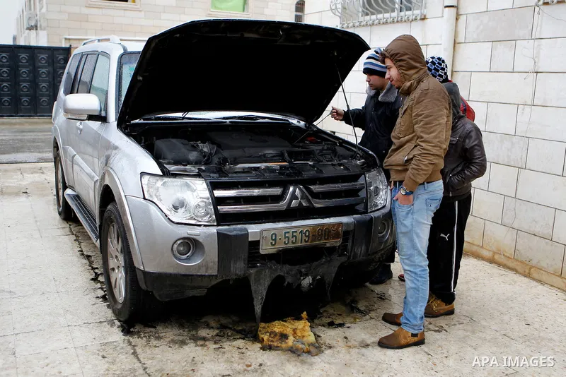 Palestinians inspect the damaged car of Palestinian Hamas law maker Hatem Qafisha after it was burnt by unknown people in the West Bank city of Hebron, January 24, 2016. The car was burnt two hours before Qafisha's arres...