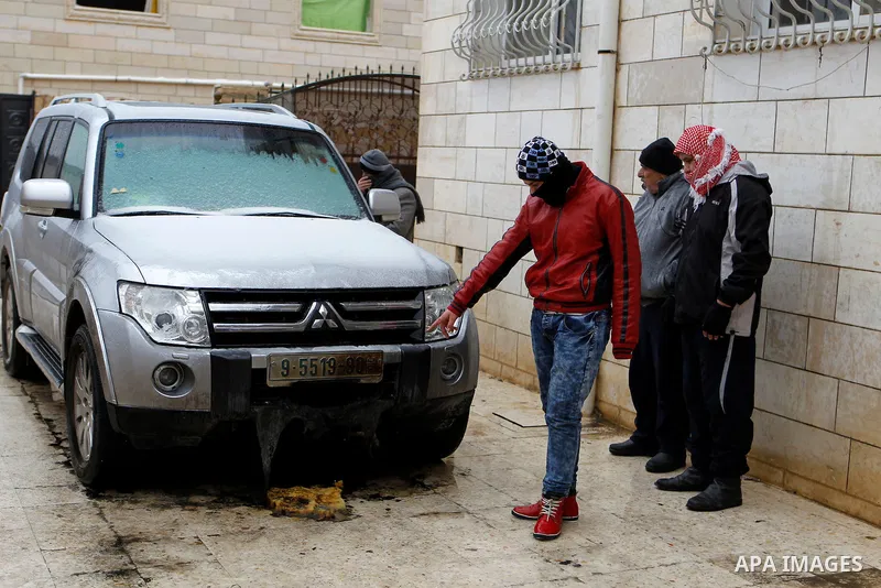 Palestinians inspect the damaged car of Palestinian Hamas law maker Hatem Qafisha after it was burnt by unknown people in the West Bank city of Hebron, January 24, 2016. The car was burnt two hours before Qafisha's arres...