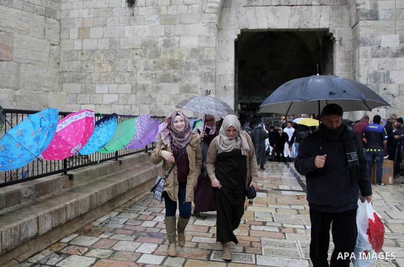 Palestinians walk in front of Damascus gate in Jerusalem's Old city on a rainy day on Jan. 24, 2016. Photo by Mahfouz Abu Turk