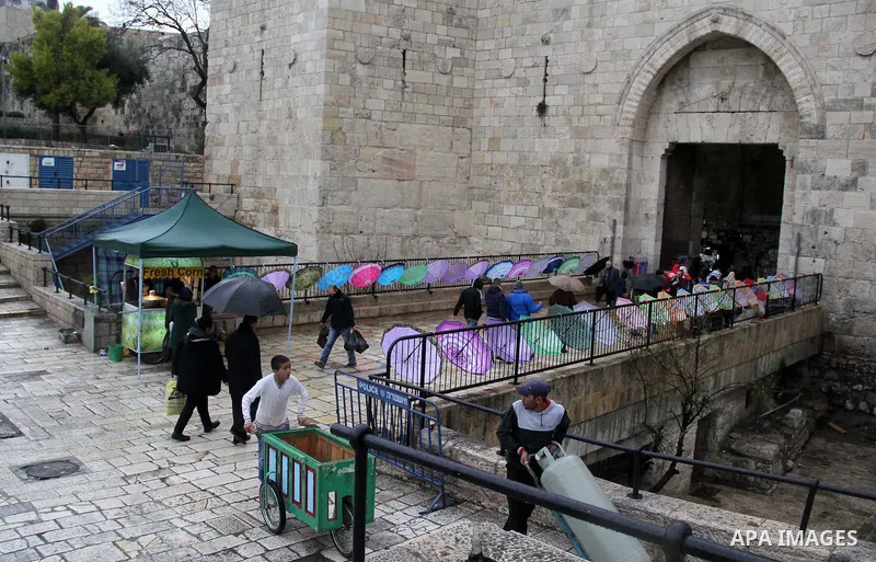 Palestinians walk in front of Damascus gate in Jerusalem's Old city on a rainy day on Jan. 24, 2016. Photo by Mahfouz Abu Turk