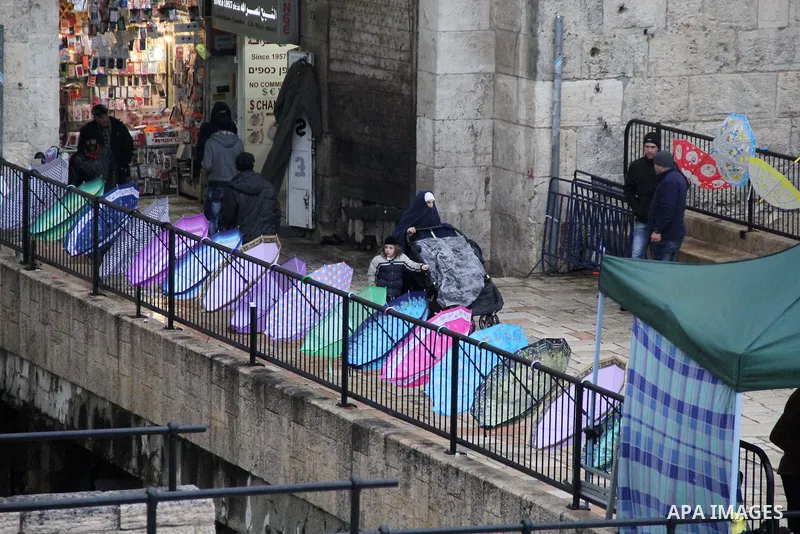 Palestinians walk in front of Damascus gate in Jerusalem's Old city on a rainy day on Jan. 24, 2016. Photo by Mahfouz Abu Turk
