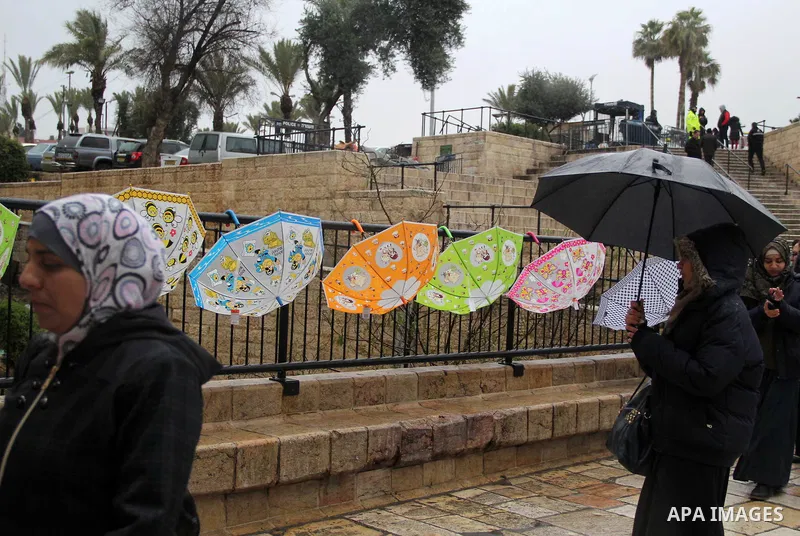Palestinians walk in front of Damascus gate in Jerusalem's Old city on a rainy day on Jan. 24, 2016. Photo by Mahfouz Abu Turk
