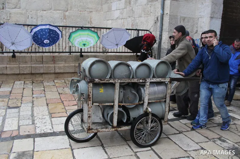 Palestinians walk in front of Damascus gate in Jerusalem's Old city on a rainy day on Jan. 24, 2016. Photo by Mahfouz Abu Turk