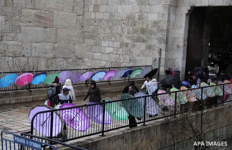 Palestinians walk in front of Damascus gate in Jerusalem's Old city on a rainy day on Jan. 24, 2016. Photo by Mahfouz Abu Turk