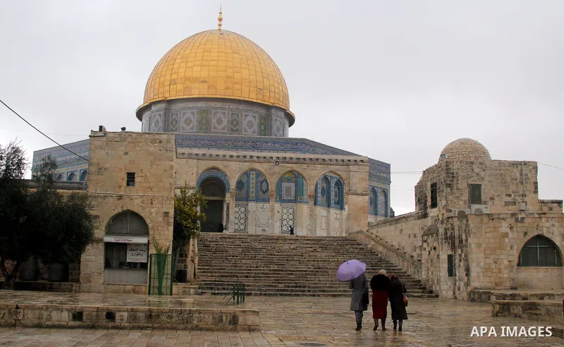 Palestinians walk in front of Dome of the Rock mosque at the Al-Aqsa mosque compound in Jerusalem's Old city on a rainy day on Jan. 24, 2016. Photo by Mahfouz Abu Turk