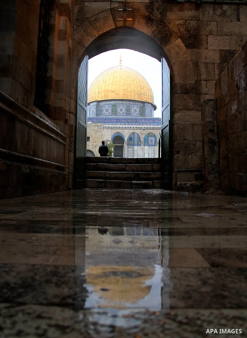 Palestinians walk in front of Dome of the Rock mosque at the Al-Aqsa mosque compound in Jerusalem's Old city on a rainy day on Jan. 24, 2016. Photo by Mahfouz Abu Turk