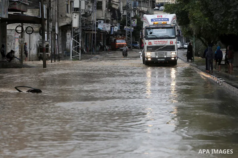 Palestinian boys walk though a flooded road on a rainy day in Gaza city, January 24, 2016. Photo by Mohammed Asad