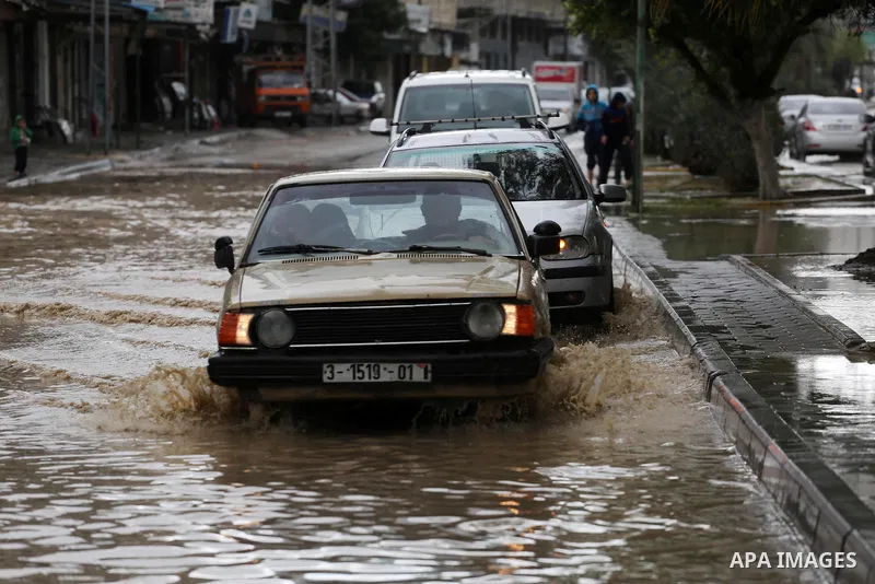 Palestinian boys walk though a flooded road on a rainy day in Gaza city, January 24, 2016. Photo by Mohammed Asad
