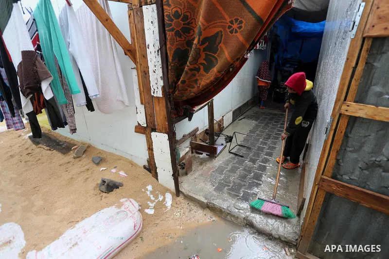 A Palesitinan boy living in containers as temporary replacement for their houses that were destroyed by what witnesses said was Israeli shelling during a 50- day-war in 2014 summer, cleans rain water outside his makeshif...