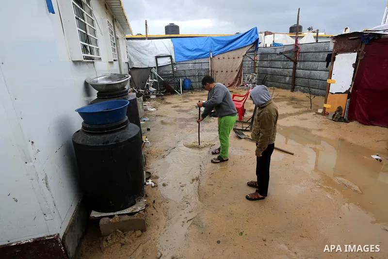 A Palesitinan boy living in containers as temporary replacement for their houses that were destroyed by what witnesses said was Israeli shelling during a 50- day-war in 2014 summer, cleans rain water outside his makeshif...