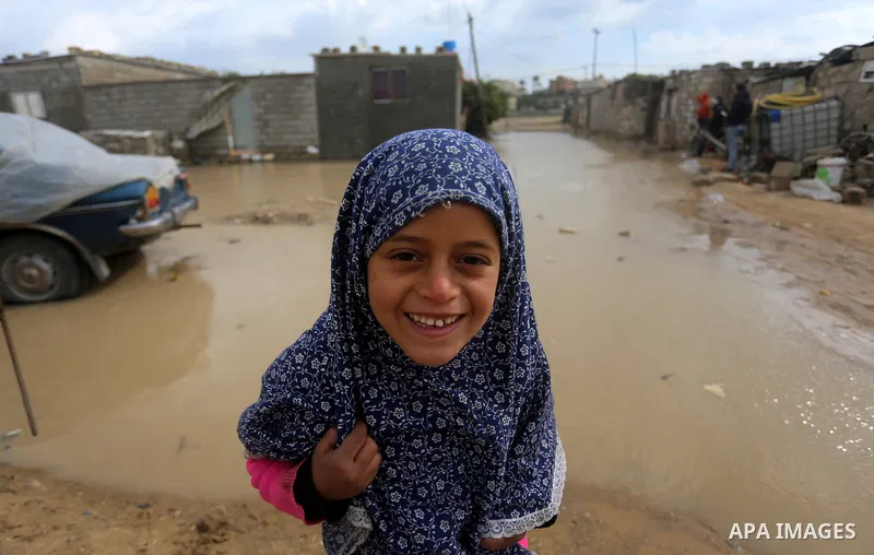 A Palestinian girl stand outside her family house on a rainy day, in Khan Younis in the southern Gaza Strip, January 24, 2016. Photo by Yasser Qudih