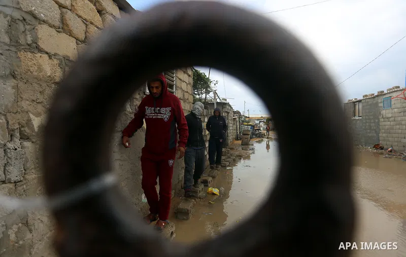 Palestinians cross a road flooded with rainwater following heavy rains, in Khan Younis in the southern Gaza Strip January 24, 2016. Photo by Yasser Qudih
