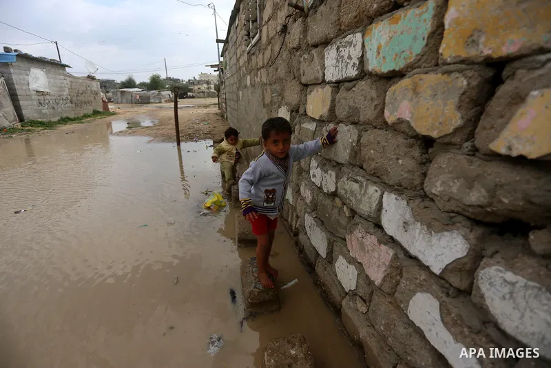 Palestinian boys cross a road flooded with rainwater following heavy rains, in Khan Younis in the southern Gaza Strip January 24, 2016. Photo by Yasser Qudih