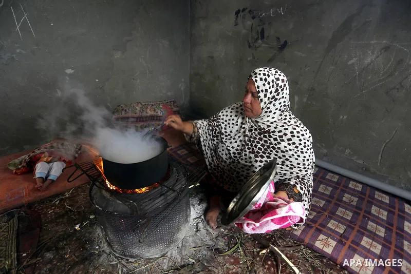 A Palestinian woman cooks food on a rainy day, in Khan Younis in the southern Gaza Strip, January 24, 2016. Photo by Yasser Qudih