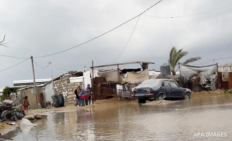 Palestinians cross a road flooded with rainwater following heavy rains, in Khan Younis in the southern Gaza Strip January 24, 2016. Photo by Abed Rahim Khatib