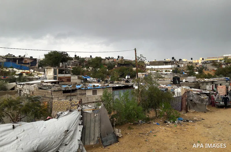 Palestinians walk at street on a rainy day, in Khan Younis in the southern Gaza Strip, January 24, 2016. Photo by Abed Rahim Khatib
