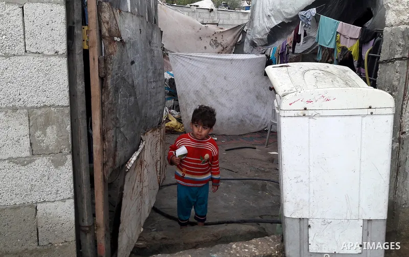 A Palestinian boy looks out his family house on a rainy day, in Khan Younis in the southern Gaza Strip, January 24, 2016. Photo by Abed Rahim Khatib