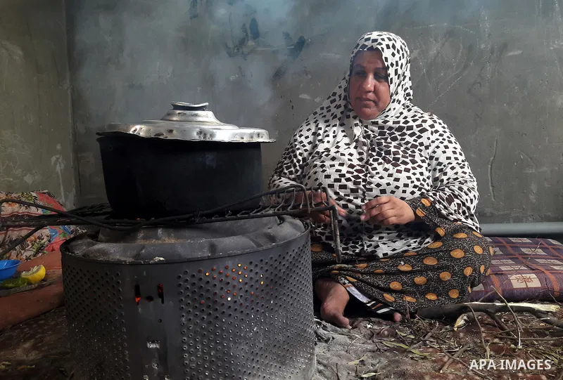 A Palestinian woman cooks food on a rainy day, in Khan Younis in the southern Gaza Strip, January 24, 2016. Photo by Abed Rahim Khatib