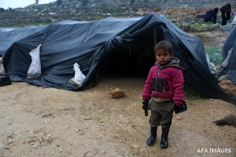 A Palestinian Bedouin boy stands next to his family's flooded tent during a rainy day in the village of Ein Qiniya near the West Bank city of Ramallah, Jan. 25, 2016. Photo by Shadi Hatem