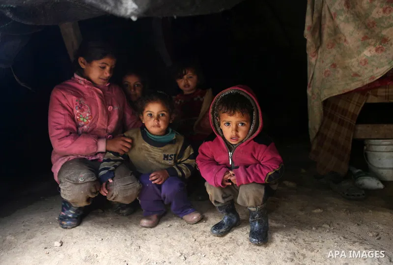 Palestinian Bedouin children sit inside their family's tent during a rainy day in the village of Ein Qiniya near the West Bank city of Ramallah, Jan. 25, 2016. Photo by Shadi Hatem