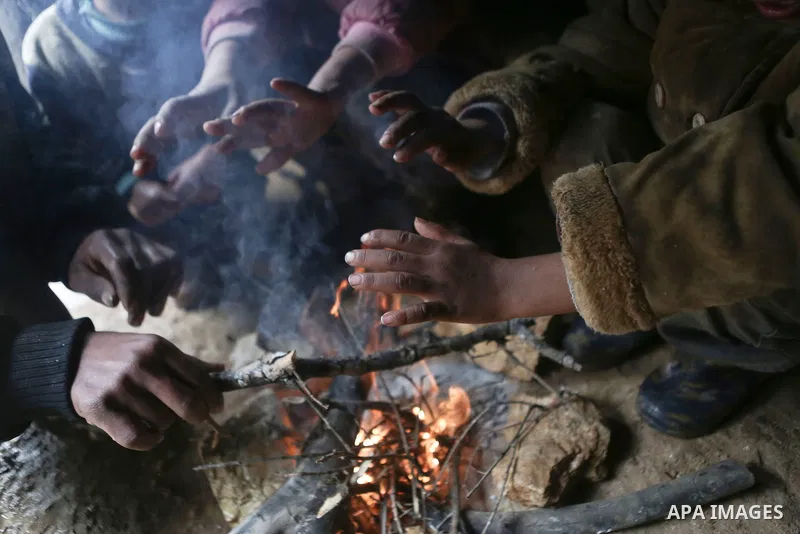 Palestinian Bedouin children warm themselves next to a fire in their family's tent on a rainy day in the village of Ein Qiniya near the West Bank city of Ramallah, Jan. 25, 2016. Photo by Shadi Hatem